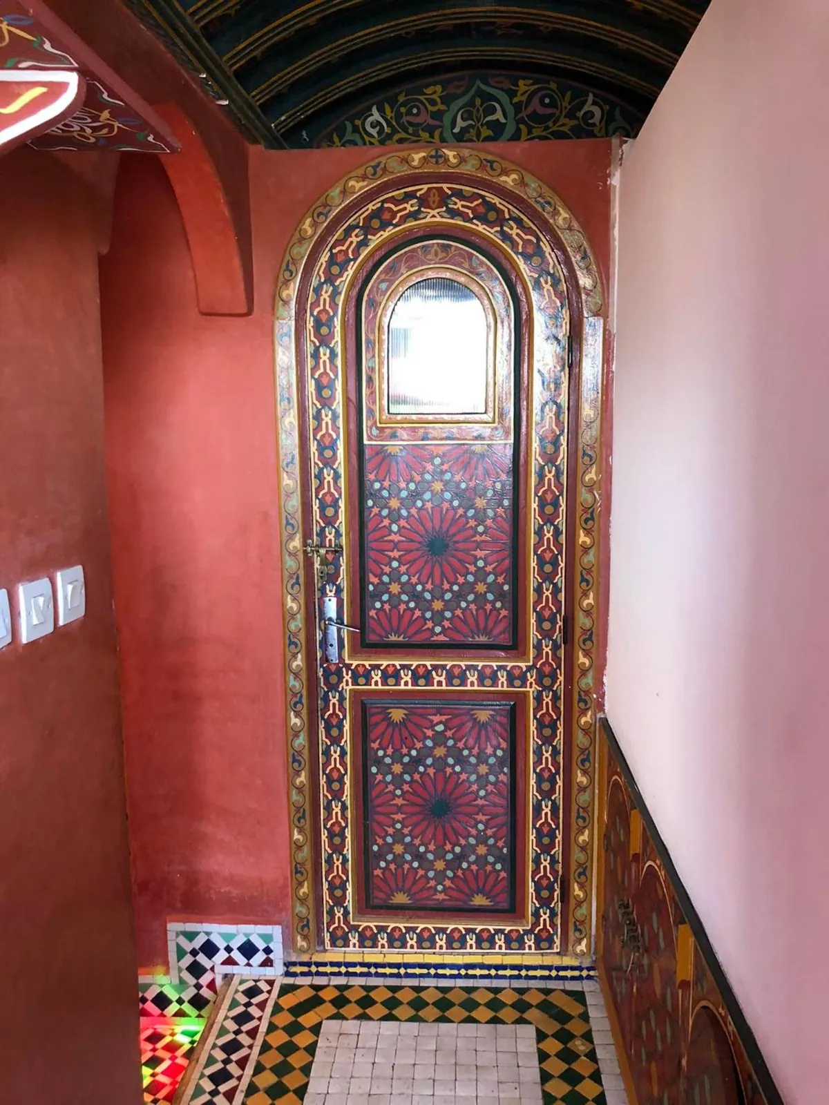 Un couloir rouge et une porte peinte