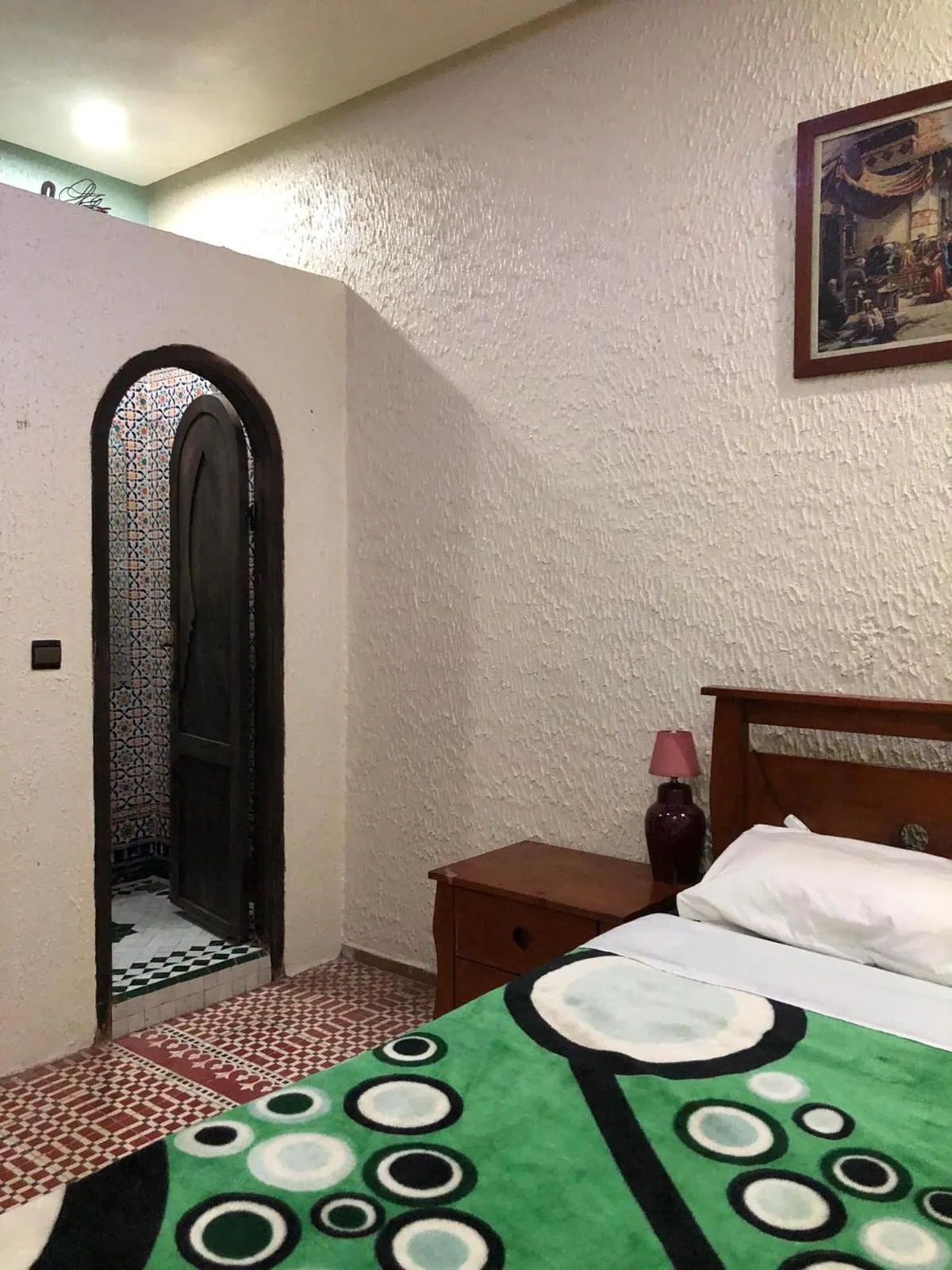 Une chambre double, porte en arc et couette verte