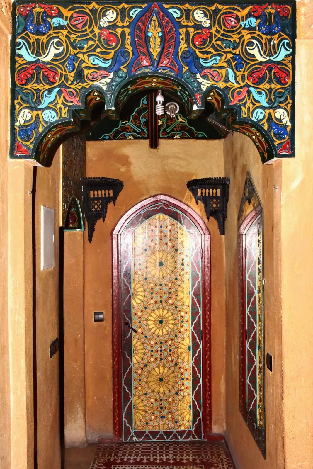 Une porte en zellige sous un linteau peint