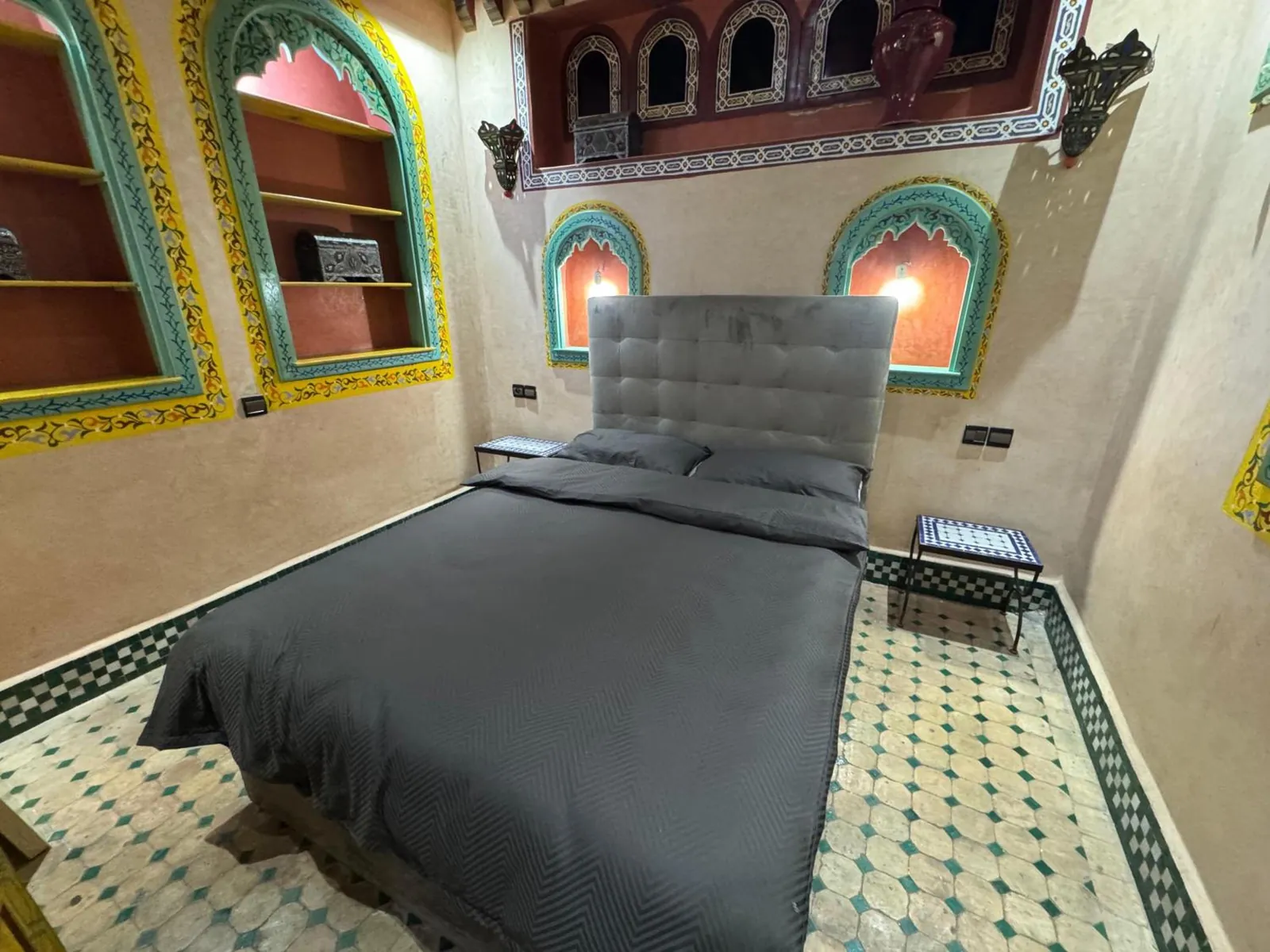 Une chambre, lit gris et niches éclairées